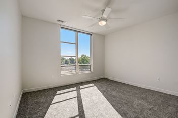 a bedroom with a large window and a ceiling fan